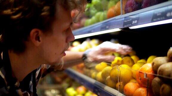 超市里店员戴着透明手套用各种各样的有机食品填满柠檬货架超市店员正在把水果放在商店的货架上