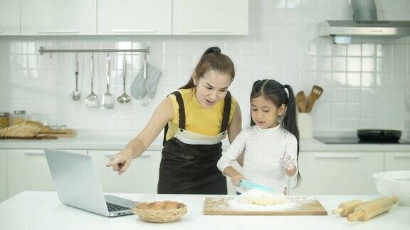 母亲和女儿在家里的厨房进行在线烘焙课程