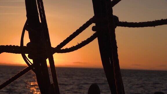 透过一艘旧帆船的护桅索具看日落海景慢动作视频