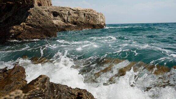 绿松石色的泡沫海浪以慢动作冲击着海岸线上的岩石