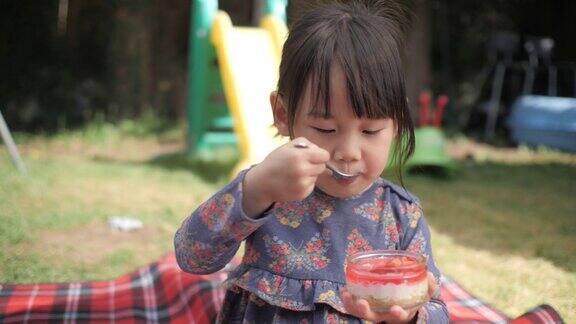 蹒跚学步的小女孩在家花园里吃起司蛋糕