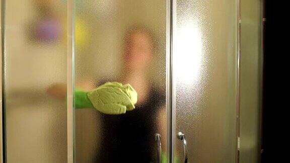 一个女人在打扫浴室的淋浴房的门