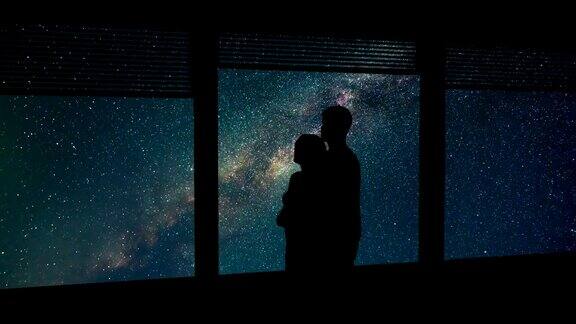 在流星雨的背景下男人和女人在窗边拥抱时间流逝