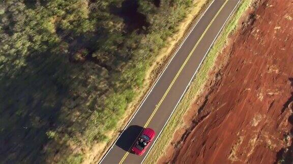 空中特写:一辆红色的敞篷车在乡村公路上行驶