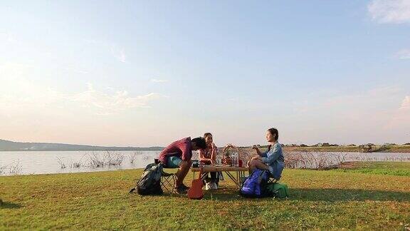 一群亚洲朋友玩尤克里里和花时间在夏季假期野餐他们在假期很快乐玩得很开心
