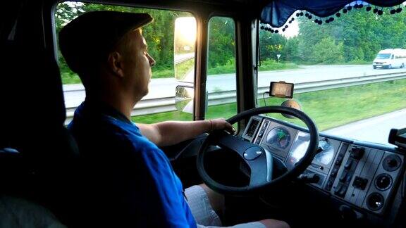 卡车司机骑在乡村的特写戴着帽子的人控制着他的卡车小心地看着交通明亮的夕阳映照在汽车的侧镜上慢镜头:卡车司机在乡间行驶的特写戴着帽子的人