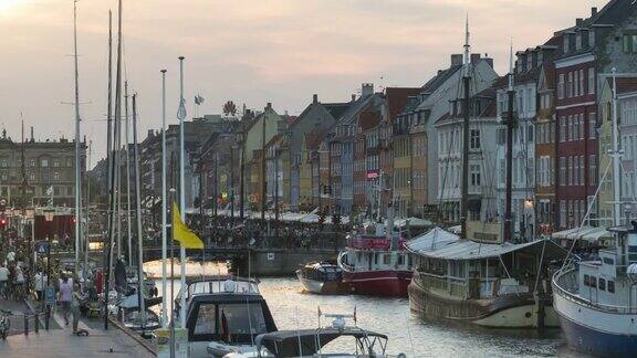 丹麦哥本哈根尼哈芬市色彩缤纷的传统房屋人们在夕阳下享受餐馆和酒吧