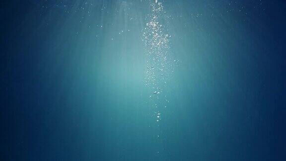 美丽的水下阳光光束与上升的气泡幕