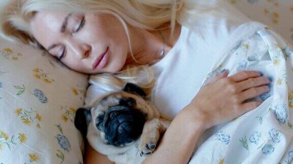 和小狗哈巴狗睡在床上的女人