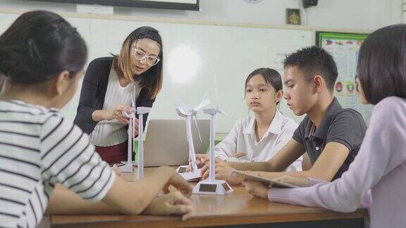 教育老师饶有兴趣地给孩子们讲解风力涡轮机的操作