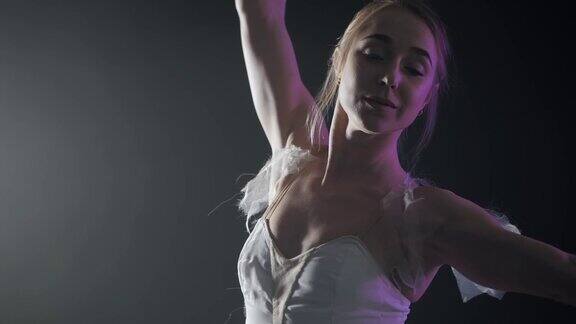 优雅性感的芭蕾舞女演员在白色芭蕾舞裙的舞蹈元素古典或现代芭蕾在黑暗与紫色的光和黑色的背景烟慢动作