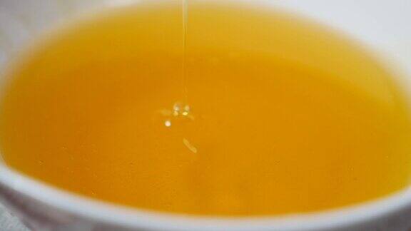 近距离拍摄的蜂蜜滴落在蜂蜜勺在一个装满蜂蜜的碗