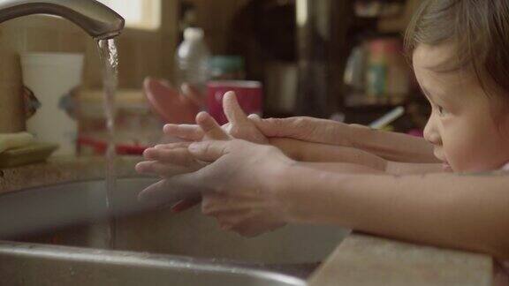 年轻的母亲和儿子在厨房的水槽洗手