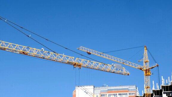 一栋多层建筑的建造两座建筑起重机顶着天空在建筑工地工作