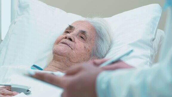 灰白头发的女人躺在治疗床上回答医生的问题