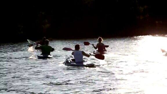 日落时分年轻人在湖中划独木舟