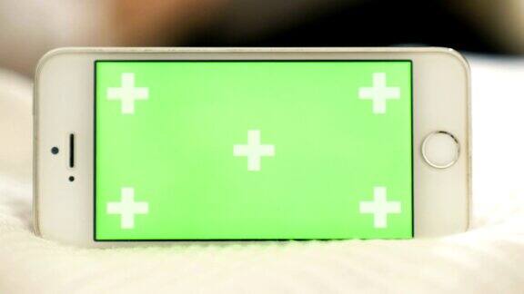 智能手机与色度键绿色屏幕在房间的特写-绿色屏幕手持智能手机