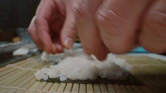 日本厨师在做寿司时把米饭放在海苔片上的侧视图