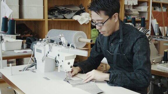 中等拍摄的中年裁缝工作缝纫机在他的设计工作室