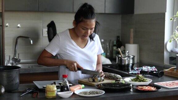 在切菜板上熟练的妇女把寿司卷和寿司卷切成一片