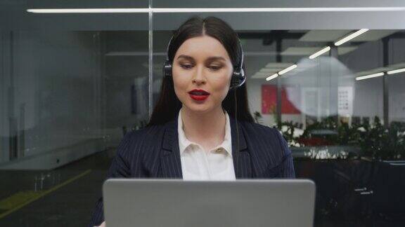年轻女性客服人员或销售人员戴着耳机通过笔记本电脑与客户进行视频通话