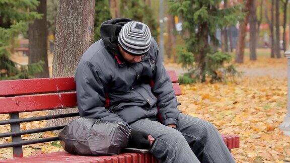 男性酗酒成瘾者睡在秋天公园的长椅上酗酒问题