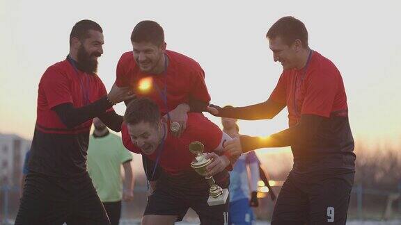 激动的足球运动员在赢得奖杯后一起庆祝