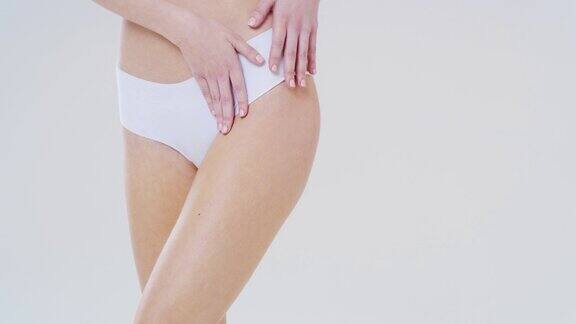 慢镜头近距离的女人显示她的完美的身体臀部和臀部没有脂肪团治疗后孤立在一个白色的背景