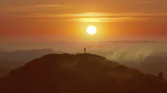 那只拿着烟雾弹的雄鸟站在山上背对着明亮的日出