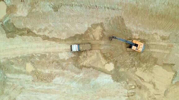 鸟瞰图镜头(俯视图)挖土机铲粘土土到一辆自卸卡车