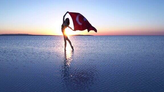 美丽的舞者举着土耳其国旗在湖上的Cinemagraph有风的一天