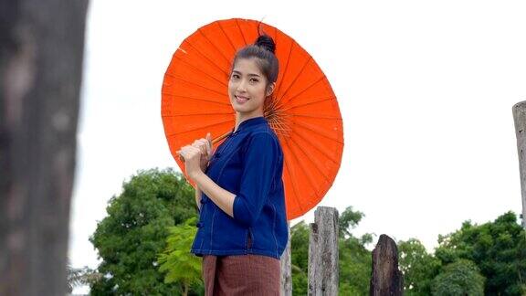 美丽的泰国女人穿着传统风格拿着红色伞在户外