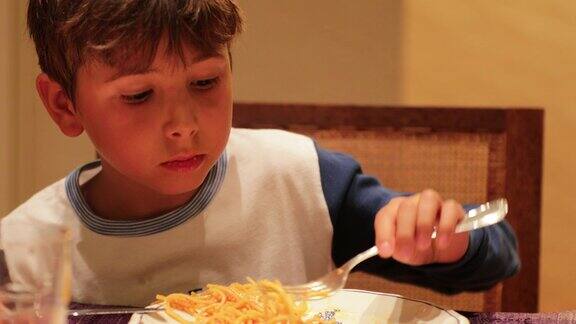 孩子晚餐吃意大利面小男孩晚餐用叉子吃了一口意大利面