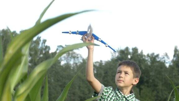 一个男孩在玉米地里玩玩具飞机他梦想成为一名飞行员