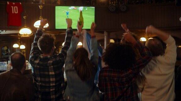 一群朋友在体育酒吧看电视直播的足球比赛兴奋的球迷欢呼和喊叫当球队进球并赢得足球世界杯时年轻人庆祝