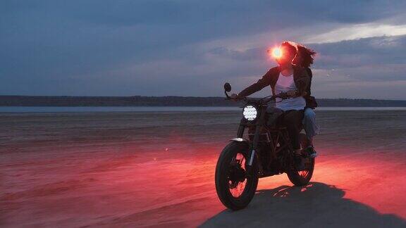 夫妇日落在海滩上骑摩托
