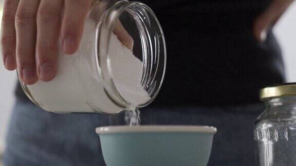 将糖从玻璃罐中倒入碗中准备烘烤用白桦糖测量成分