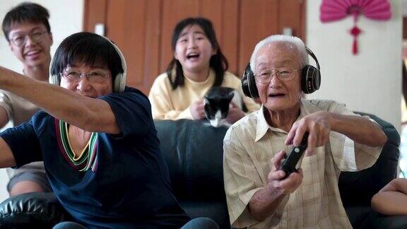 2名亚裔中国祖父母在家里和孙辈玩电子游戏
