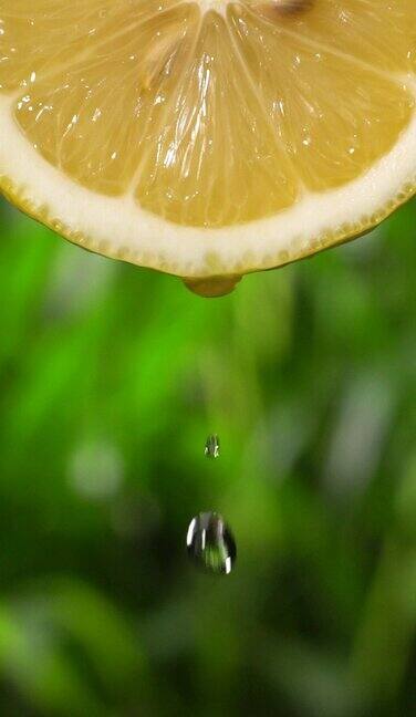 垂直和慢动作:许多液体从柠檬片在绿色散焦