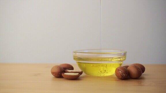 摩洛哥坚果油倒入玻璃碗中白色背景上有摩洛哥坚果种子基于摩洛哥坚果油的化妆品概念