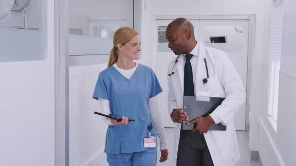 穿白大褂的医生和穿手术服的护士在医院走廊里讨论数字平板电脑
