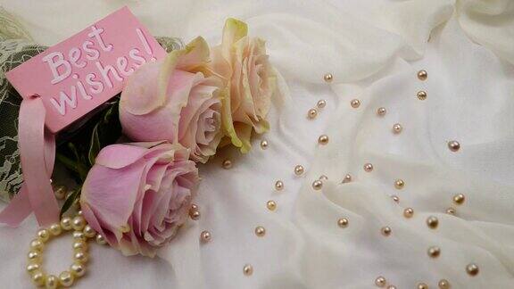 粉红色的珍珠珠落在一束粉红色的玫瑰和一张卡片上祝福慢镜头