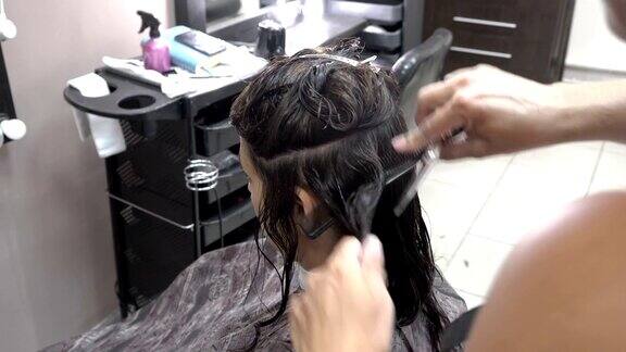 美发师在美容院给一个女孩剪黑色的头发特写镜头后视图侧视图4k