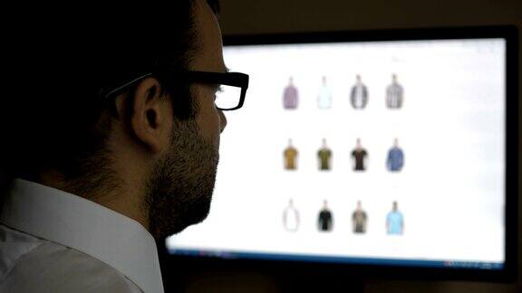 一名男子在网上服装店看货坐在桌子前电脑网上购物PC显示器显示模糊的饲料页