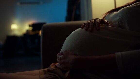 特写孕妇感受到爱她的胎儿在晚上放松