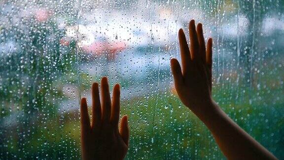 女人用手碰了碰窗户上的雨滴