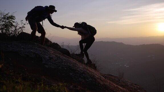 徒步旅行者互相帮助攀上山顶