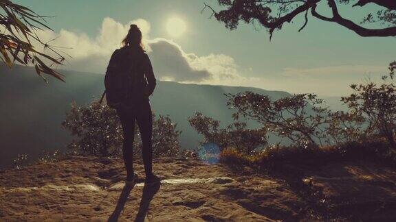 女子站在山顶欣赏日落美景的慢镜头