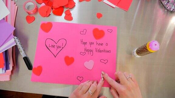 一位女性制作了一张快乐的情人节卡片上面写着爱你