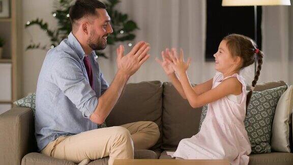 快乐的爸爸和女儿在家里玩拍手游戏